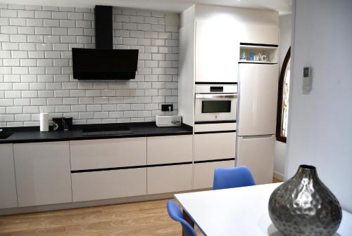米拉马尔Casa VALOLI PLAYA MIRAMAR的厨房配有白色橱柜、桌子和电视。