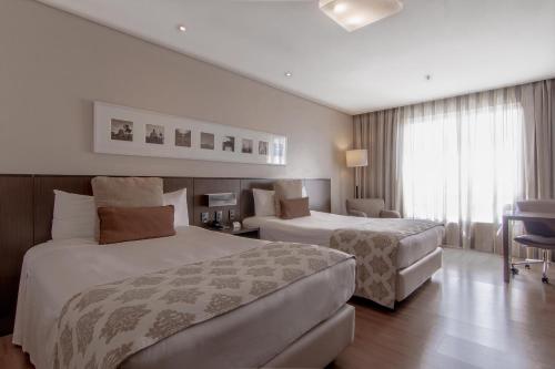 阿雷格里港阿雷格里港德维尔总理酒店的酒店客房设有两张床和一张桌子。