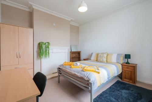 谢菲尔德Spacious & Homely, 4 BR, Parking, Close to Centre的一间卧室配有一张床、一张桌子和一张桌子