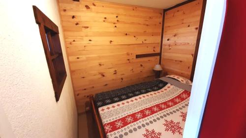 梅塔比耶Au Doubs Refuge的一间小卧室,配有一张位于木制房间内的床