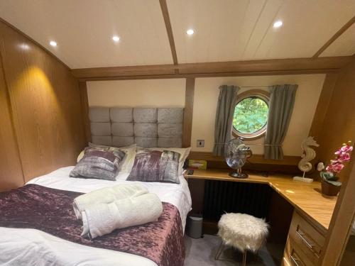 阿克斯桥Luxury boat - The Thistle Dream的一间卧室配有一张床、一张书桌和一个窗户。