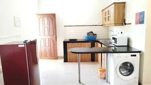 瓦尔恰Seacoast Retreat- Lovely 2 BHK apartment with pool的厨房配有桌子和洗衣机。