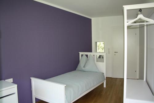 因斯布鲁克Felseck Zimmer的卧室配有白色的床和紫色墙壁