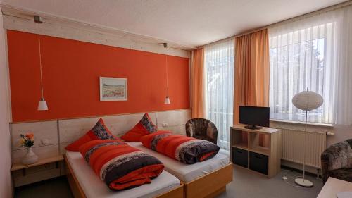 JöhstadtHotel Heilbrunnen的一间卧室拥有橙色的墙壁,配有一张带枕头的床。