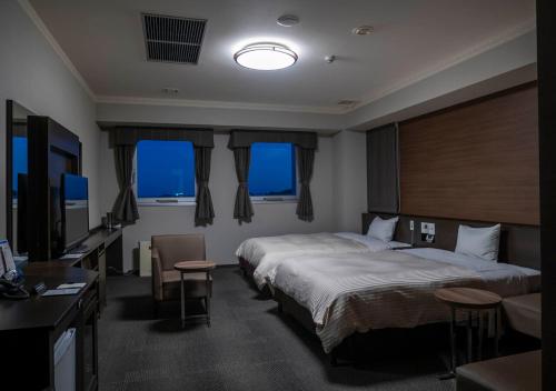 新宫市Hotel New Palace的酒店客房设有两张床和电视。