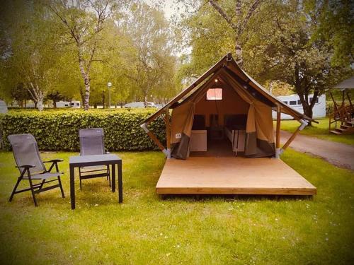 贝尔多夫Safari tent XS的草顶帐篷,配有两把椅子和一张桌子