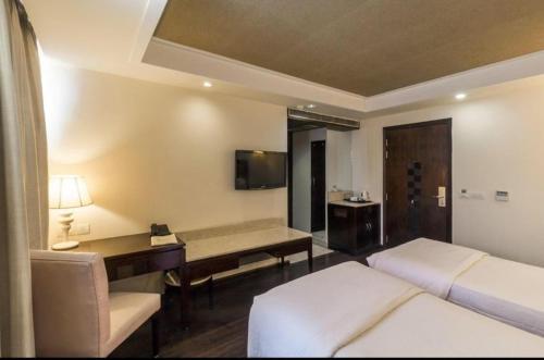 新德里Madhuban Hotel , New delhi的酒店客房设有两张床、一张桌子和一台电视。