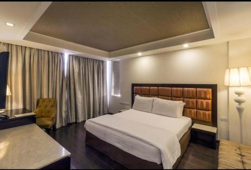 新德里Madhuban Hotel , New delhi的卧室配有一张白色大床和一把椅子