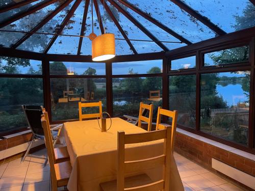 诺里奇Holly Lodge的一间带桌椅和大窗户的用餐室