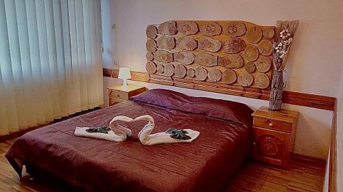 班斯科天竺葵山旅馆的一间卧室配有一张带两张天鹅形毛巾的床