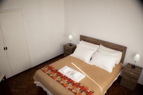 门多萨Piazza Mendoza的一间卧室配有一张带两张桌子和两盏灯的床。