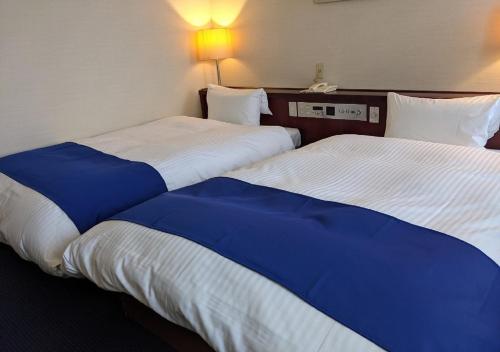 一宫市Ichinomiya City Hotel的两间相邻的床铺位于酒店客房内