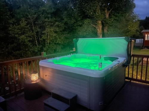 费尔顿Carre Retreat with private hot tub的夜间甲板上的绿色浴缸