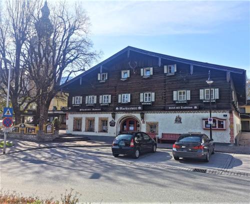 阿尔滕马克特蓬高伽斯霍夫马克特维特酒店的两辆汽车停在一座大型木结构建筑前