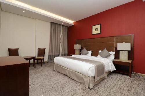 达曼Maskan Almadinah的一间卧室设有一张大床和红色的墙壁