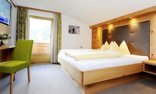 加尔蒂Apart Christine - Silvrettacard-Sommer inklusive的一间卧室配有一张大床和一张绿色椅子