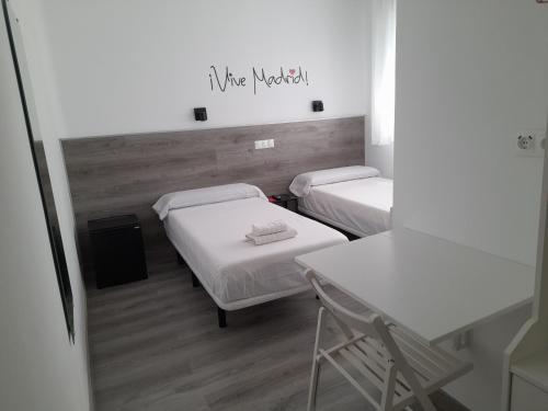 马德里CH Bueno的客房设有两张床、一张桌子和一张书桌。