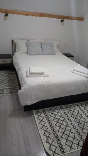 默古拉Dor de munte的卧室内的一张带白色床单和枕头的床