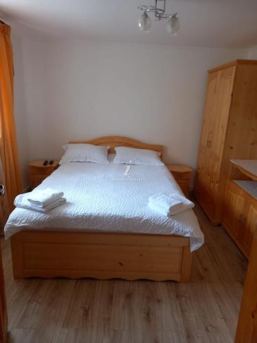 默古拉Dor de munte的一间卧室配有一张带白色床单的木床