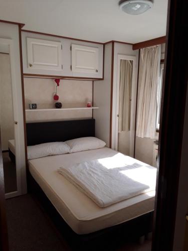 HoekMarina beach chalet nummer P0 28的一间小卧室,配有白色床单