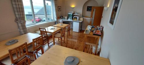 埃伦港Cala Sith Guesthouse的厨房以及带木桌和椅子的用餐室。