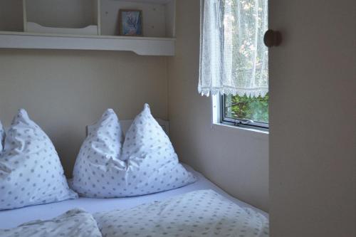 德布吉Domki holenderskie ,, Latający Holender"的一张带白色枕头的床和窗户