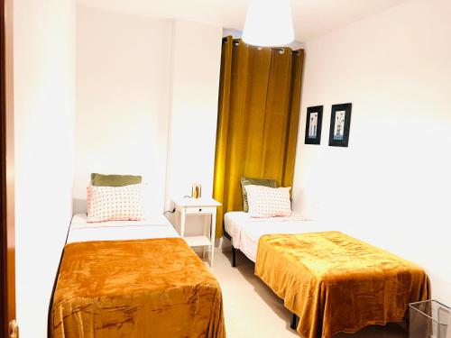卡拉德莫尔Apartamento Rincón, Ideal para familias的一间设有两张带橙色床单的床的房间