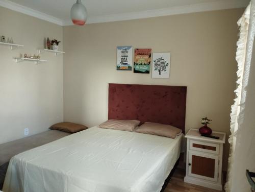 瓜拉派瑞Casa c/ Piscina e Área Gourmet, 5 min da praia.的卧室配有白色床和红色床头板