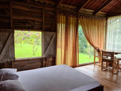 Hacienda Santa MaríaSanta Maria Volcano Lodge的一间卧室配有一张床、一张桌子和一个窗户。
