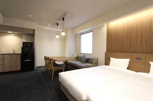 东京KOKO HOTEL Residence Asakusa Tawaramachi的酒店客房设有一张床铺、一张桌子和一间厨房。