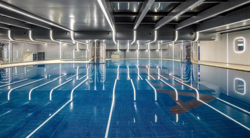 深圳深圳深航国际酒店的一座室内游泳池,铺有蓝色瓷砖地板,拥有蓝色的海水