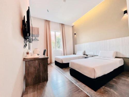 关丹KARANG TIMUR MOTEL的酒店客房设有两张床和一台平面电视。