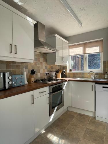 CoalportDrake Cottage - riverside retreat, Jackfield, Ironbridge Gorge, Shropshire的白色的厨房配有白色橱柜和窗户