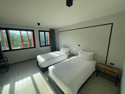 普吉镇PRIME TOWN - Posh & Port Hotel PHUKET的一间卧室设有两张床和两个窗户。