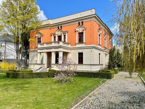 弗罗茨瓦夫Happy Living Villa的一座橙色和白色的大房子,有院子