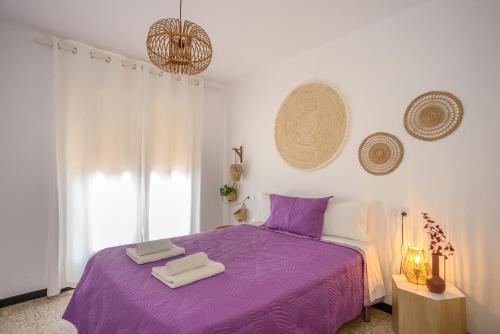 艾姆布里亚布拉瓦Empuriabrava Apartaments - nº7的一间卧室配有一张紫色床和两条毛巾
