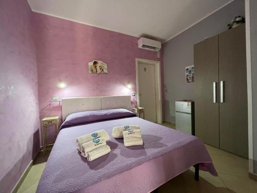 加利波利B&B Le Onde Del Mare的粉红色的卧室,配有带毛巾的床