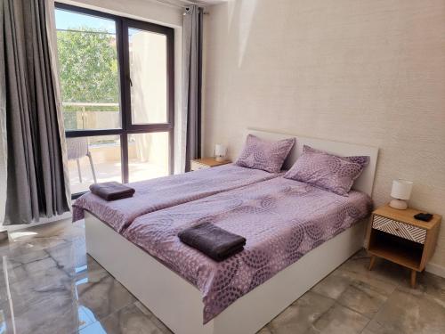 斯利文СТУДИО АВА的一间卧室配有一张带紫色床单的床和窗户。