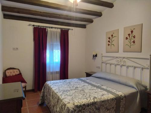 卢克Casa Rural Alamillo的一间卧室配有床和红色窗帘的窗户