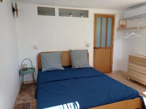 马藏l'Annexe, logement confortable avec piscine的一间卧室配有一张带蓝色床单的床和一张桌子。