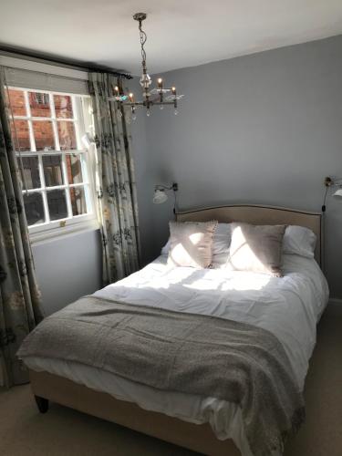 塞文河畔厄普顿Clerks Cottage的一间卧室配有一张带吊灯和窗户的床。
