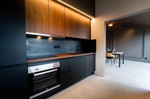蒙斯Luxury Penthouse & Terrace - Mons City Center的一间厨房,配有黑色橱柜和一间带桌子的用餐室