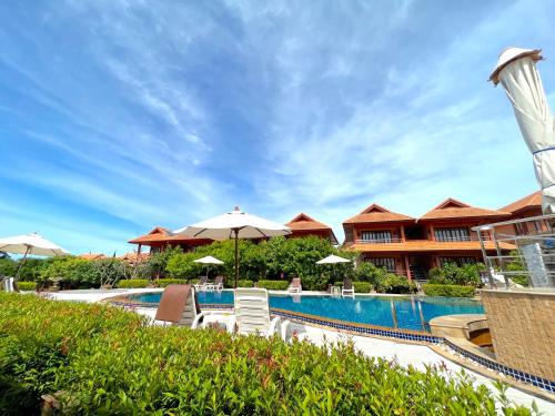 曾蒙海滩PS Thana Resort的一个带遮阳伞的度假游泳池和一个度假村