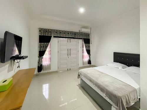 TabahpinginHotel Lucky 21 Syariah Mitra RedDoorz的一间卧室配有一张床和一台电视
