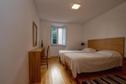波瓦桑Casa do Lado的一间卧室设有两张床、一张桌子和一个窗口。