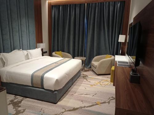 利雅德Rosa Grand Hotel的一间卧室配有一张床、一台电视和一把椅子