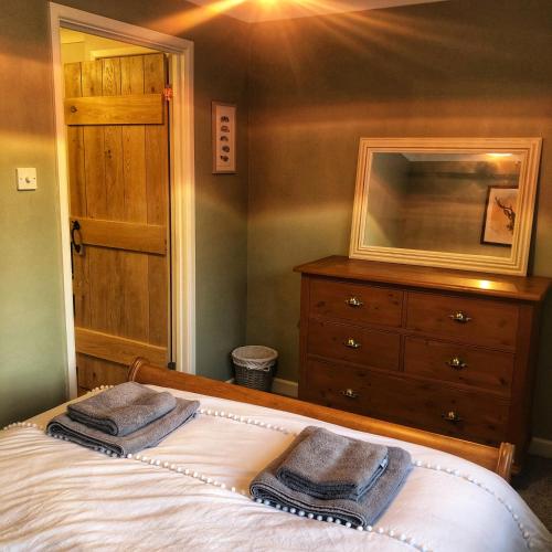 Wisborough GreenThe Rose Cottage的一间卧室配有一张床,上面有两条毛巾