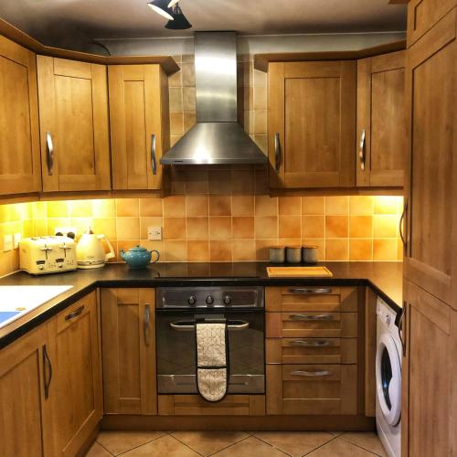 Wisborough GreenThe Rose Cottage的厨房配有木制橱柜和炉灶烤箱。