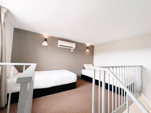 关丹KARANG TIMUR MOTEL的一间带两张床的小卧室和楼梯