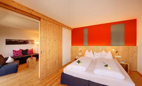 罗登戈Hotel Tirolerhof的卧室配有一张白色的大床和一张沙发。
